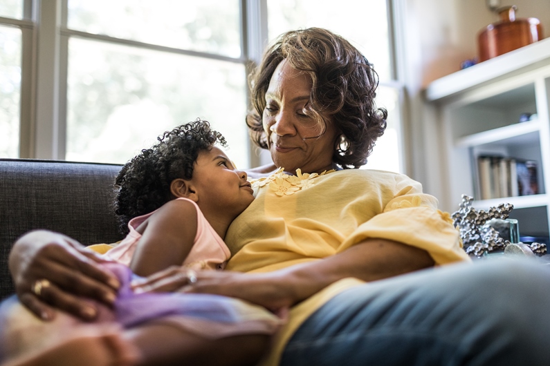 an adult sitting on a couch with a child looking up at them
