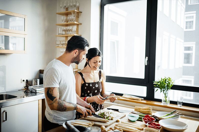 a man and woman in a kitchen preparing food